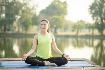 Young woman practicing yoga, breathing, meditation in lotus pose on a yoga mat
