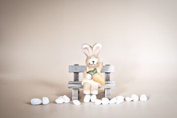 A baby bunny easter rabbit sitting on a bench looking around, on light background. Lovely bunny...