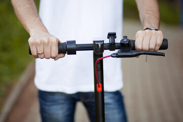 Man hands hold steering wheel of electric scooter outdoor and ready to go