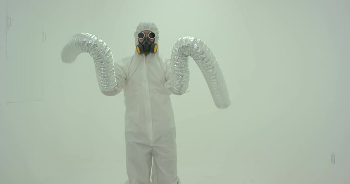Strange silhouette of man in chemical protection suite with very long sleeves looking like monster hands dancing in front of white wall. Slow motion