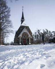 Fototapeta na wymiar man standing in front of a chapel in the snow