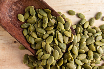 Roasted pumpkin seeds in a wooden spoon on wooden background