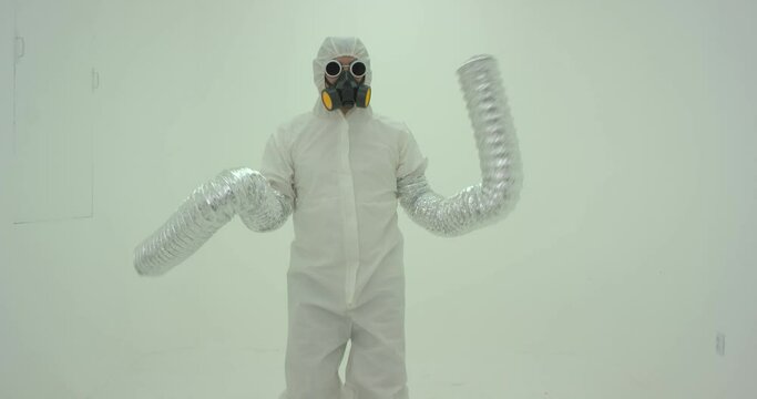Strange silhouette of man in chemical protection suite with very long sleeves looking like monster hands dancing in front of white wall. Slow motion