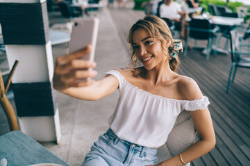 Smiling woman taking selfie on smartphone in cafe