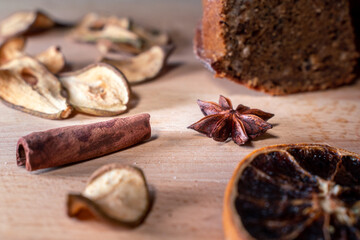 Still life with homemade cake, jar with honey and dipper, cinnamon, dried fruits, star anise on a wooden board. Small healthy snacks to enjoy during coffee break.