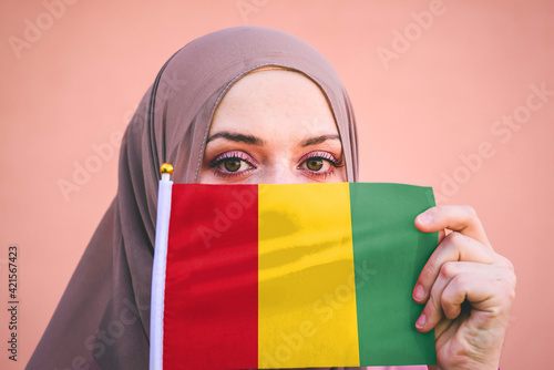 Muslim woman in hijab holds flag of Guinea