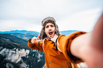Fototapeta na wymiar Hiker taking a selfie with smart phone mobile on the top of the mountain - Man hiking outdoors - People, sport and technology concept