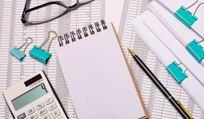 On the table there is a blank notebook with a place to insert text, a pen, glasses and reports. Close-up of the workplace. Template. Business concept