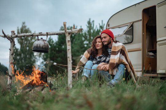 Couple In A Checkered Plaid Roasting Marshmallows On Fire Near The Trailer Home.