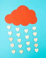 Rain of hearts. Concept of Valentine’s Day from made of a blue background and a red cloud from which hearts fall.