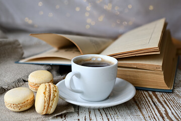 Сup of coffee, makroons and a book on the table.