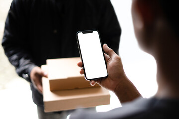 cashless payment gesture. a man holding a phone is transacting using a cash-free method with the courier. white screen phone mockup. the empty space for advertise, ui payment design, etc.