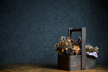 Fototapeta premium Composition of dried flowers in a wooden basket on dark background