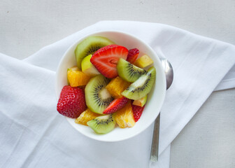 Flat lay of healthy fresh delicious fruit salad with strawberries, orange, apple and kiwi. Bowl of healthy food.