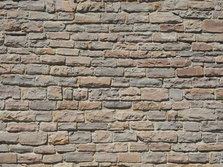 A wall with rough and grungy masonry of different sizes illuminated by sunlight. Not seamless texture