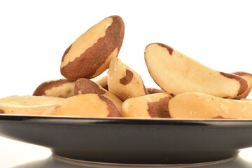 Several ripe organic Brazil nuts on a saucer, close-up. The background is white.