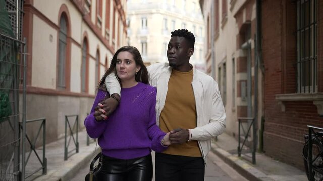 Young interracial couple walking together, modern millennial boyfriend and girlfriend in street