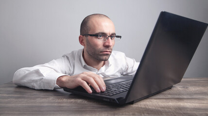 Caucasian man wearing glasses working with laptop.