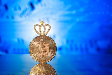 Metallic bitcoin coin with shiny crown on blue background. Bitcoin leadership business concept....