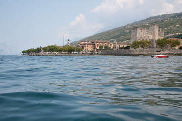 Naklejka premium Panorama Ansicht von Torri del Benaco am Gardasee, Provinz Verona und Blick auf die mittelalterliche Scaligerburg und die vielen Restaurants, Bars und Cafés und Terrassen mit Seeblick