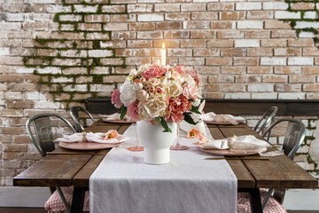 Closeup view of dreamy cute table decor with glasses flowers and lit candles. Wedding easter birthday holiday setup on a wooden table