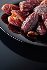 Dried sweet dates on a black plate.