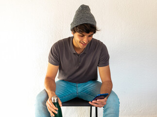 young man student sitting holding a bottle and chatting with a phone over white background