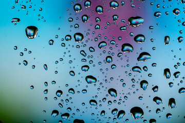 Beautiful multi-colored water droplets on a glass