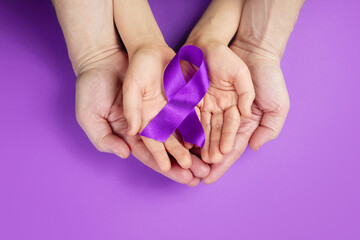 Purple day. World epilepsy day. Hands holding purple ribbon on purple background