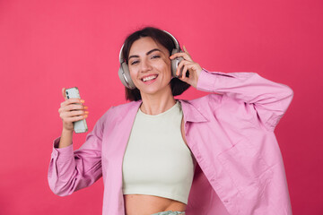 Happy positive woman in headphones on pink red background positive dancing moving enjoying sound