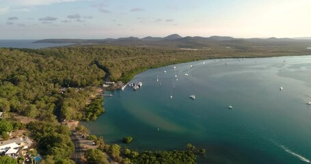 Reverse tracking aerial view of the township of Seventeen Seventy and marina on river outlet at late afternoon in sunset light,Queensland,Australia