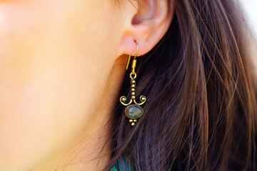 Detail of female ear wearing stone mineral floral shape bead earring