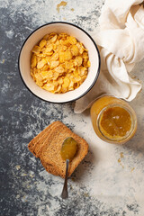 Breakfast with a bowl full of cereal, mandarin marmelade and toasted bread