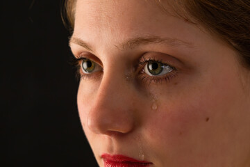 Portrait of upset woman crying in close up on black background