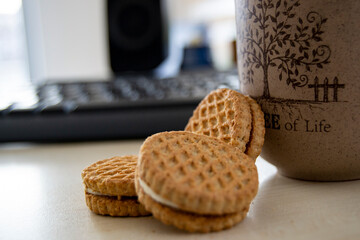 coffee and biscuits, keyboard, monitor, table in office environment