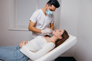 Obraz premium Young brunette woman receiving plastic surgery injection on her face