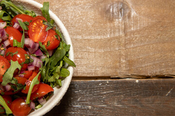 A bowl of tomatoes and herbs on a wooden table