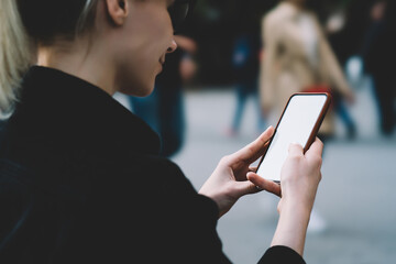 Satisfied young woman messaging on smartphone in street