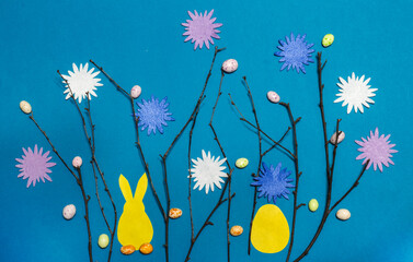 Fototapeta na wymiar Spring Easter background with your own hands with branches decorated with flowers and sweets and a hare with an egg