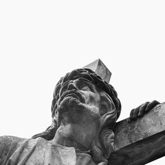 Bottom view of an ancient statue of Jesus Christ with cross. Close up. Selective focus on eyes....