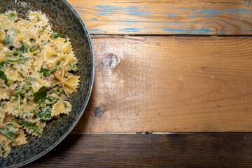 A delicious plate of Pancetta Parmesan and Pea Pasta on a wooden kitchen table