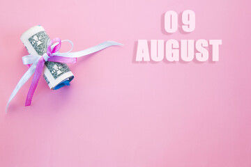 calendar date on pink background with rolled up dollar bills pinned by pink and blue ribbon with copy space. August 9 is the ninth day of the month