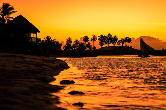 Silhueta de jangada num rio durante p&ocirc;r do sol.