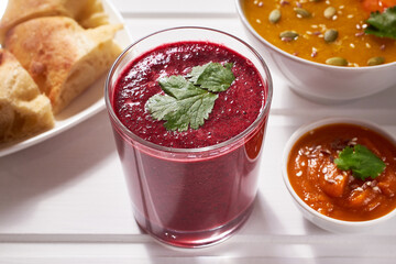 Beetroot smoothie with fresh herbs on a white wooden table. Healthy vegan food.
