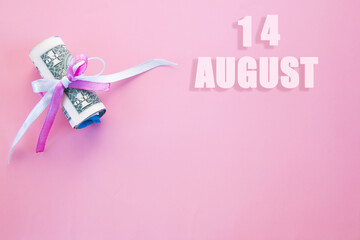 calendar date on pink background with rolled up dollar bills pinned by pink and blue ribbon with copy space. August 14 is the fourteenth  day of the month