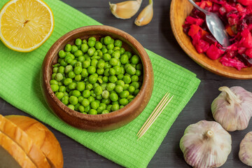 In a small wooden plate is a raw thawed green peas