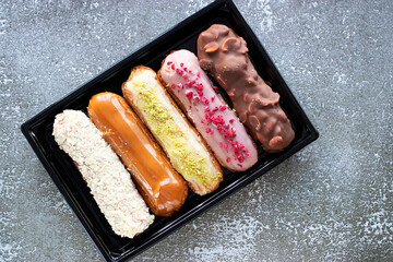 Box of eclairs on gray background.