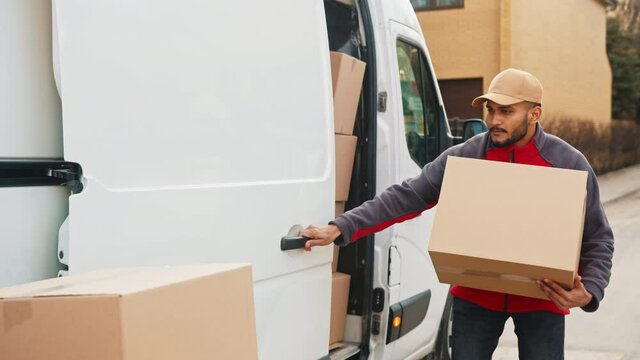Young with face mask taking a package from the van and closing the door. Delivery during covid19. High quality 4k footage