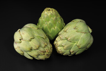 Obraz premium Still life with three fresh artichokes on black background