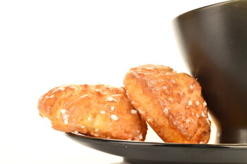 Two sweet chouquette with a cup on a saucer, close-up, isolated on white.